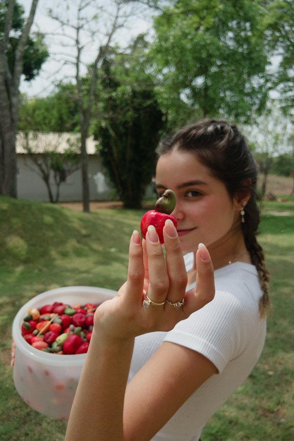 Sofia smiling and holding a cashew fruit